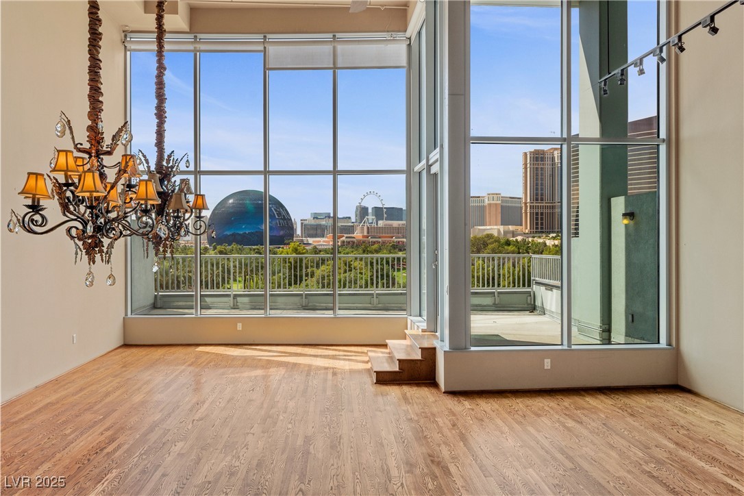 360 East Desert Inn Road, Unit 605 Las Vegas, NV 89109 - Photo 14 of 43 Unfurnished living room featuring wood finished floors, a city view, and a chandelier
