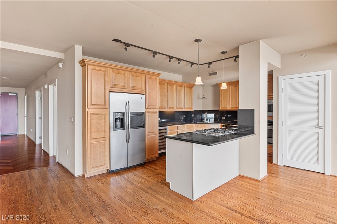 360 East Desert Inn Road, Unit 605 Las Vegas, NV 89109 - Photo 19 of 43 Kitchen featuring track lighting, stainless steel appliances, decorative backsplash, hanging light fixtures, and light wood-style flooring
