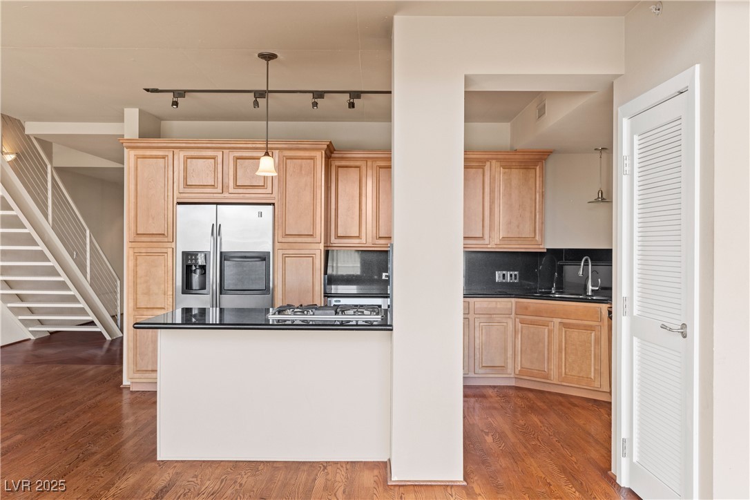 360 East Desert Inn Road, Unit 605 Las Vegas, NV 89109 - Photo 20 of 43 Kitchen with light brown cabinetry, stainless steel appliances, dark wood-style floors, rail lighting, and decorative light fixtures