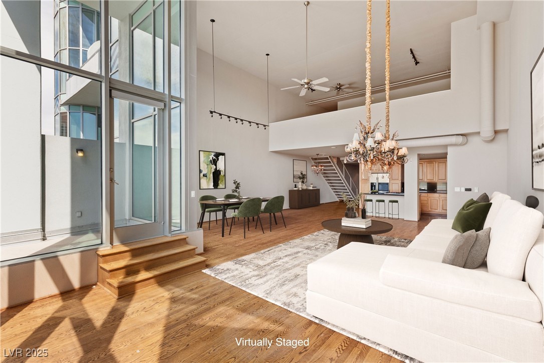 360 East Desert Inn Road, Unit 605 Las Vegas, NV 89109 - Photo 3 of 43 Virtually staged | Living area with stairs, wood finished floors, a ceiling fan, a chandelier, and a towering ceiling