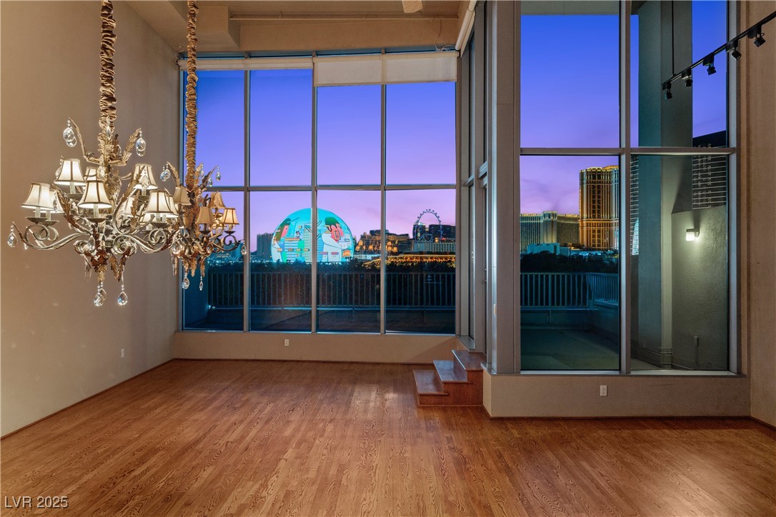 360 East Desert Inn Road, Unit 605 Las Vegas, NV 89109 - Photo 10 of 43 Empty room featuring a city view, wood finished floors, and a chandelier