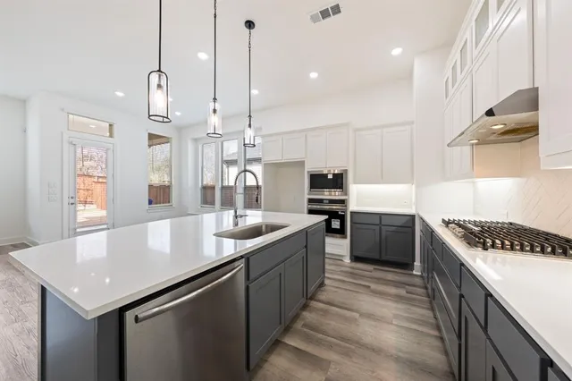 a kitchen with stainless steel appliances granite countertop a sink a counter space and cabinets