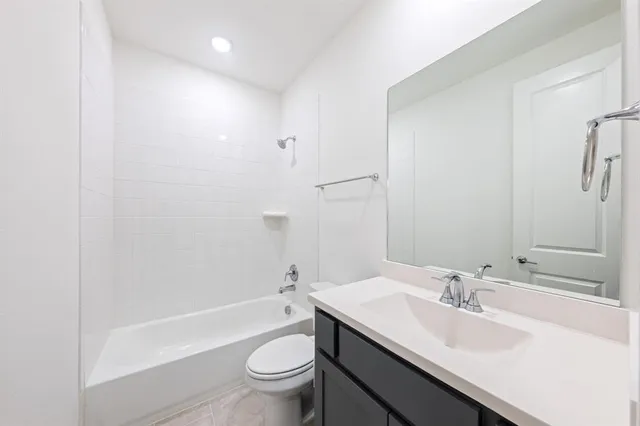 a bathroom with a bathtub shower sink vanity mirror and toilet