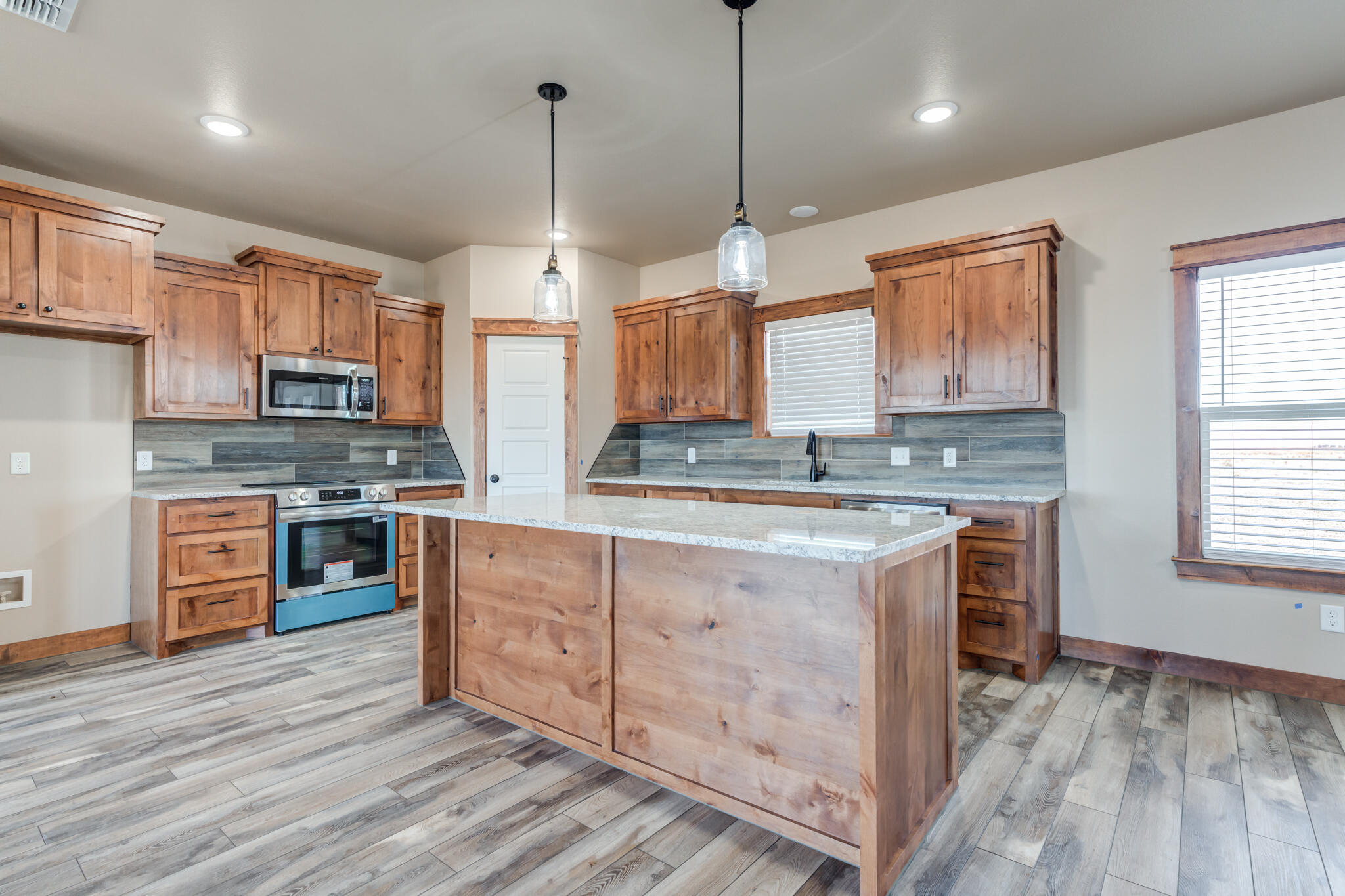 12401 North C R 2900 Lubbock, TX 79403 - Photo 12 of 40 a kitchen with stainless steel appliances granite countertop a stove a sink dishwasher a refrigerator and a oven with wooden floor