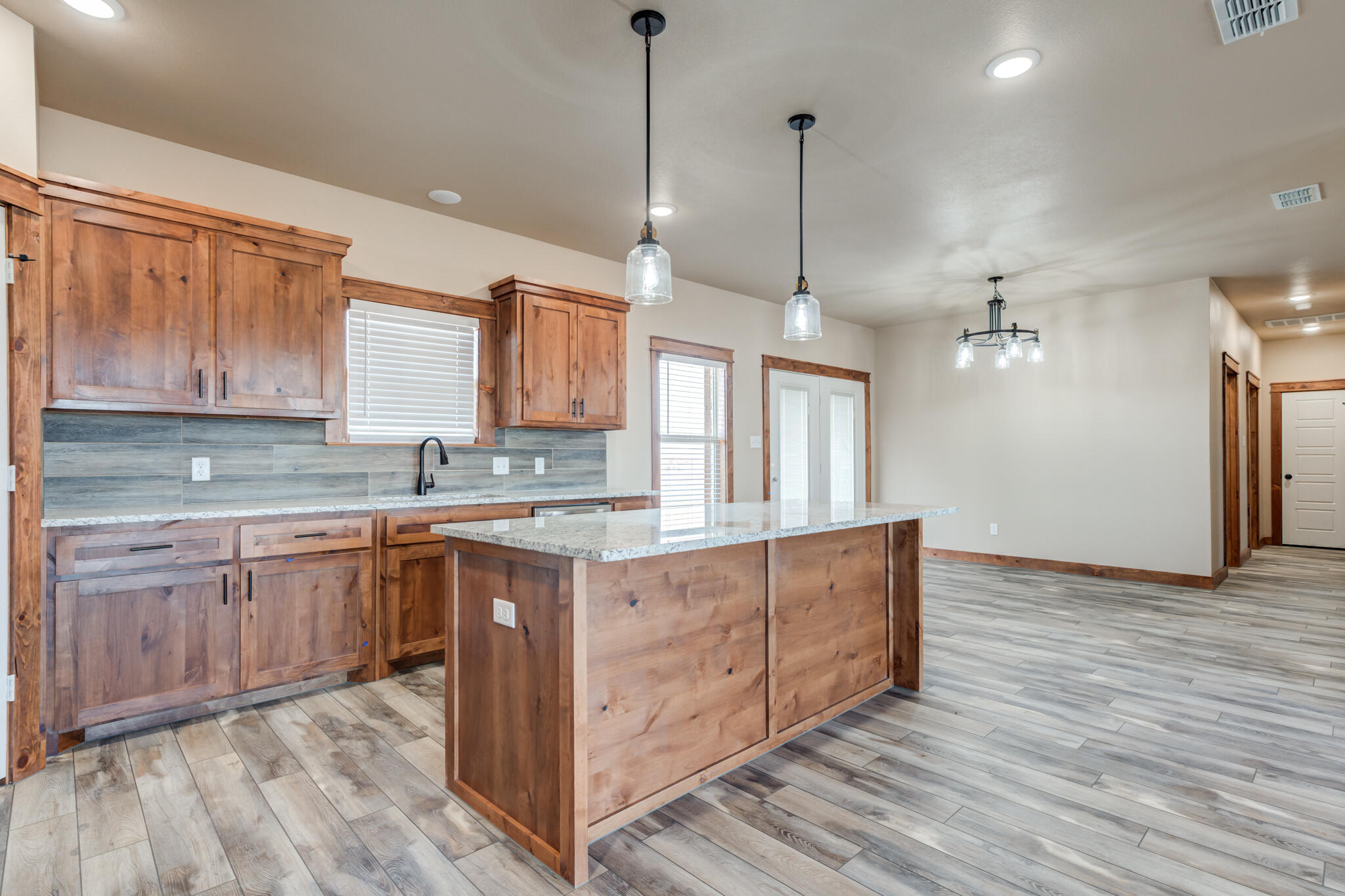 12401 North C R 2900 Lubbock, TX 79403 - Photo 14 of 40 a large kitchen with stainless steel appliances granite countertop a sink a stove a refrigerator and island with wooden floor