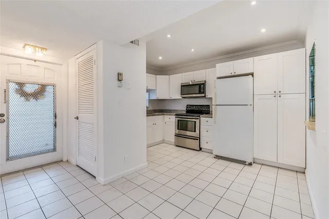 a kitchen with white cabinets and refrigerator