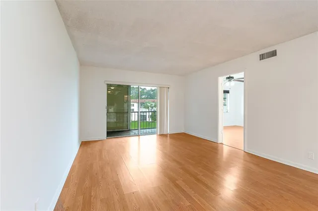 an empty room with wooden floor fan and windows