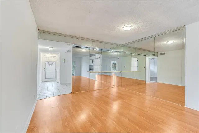 a view of an empty room with wooden floor and a ceiling fan