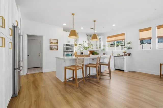 a kitchen with stainless steel appliances a dining table chairs stove and cabinets