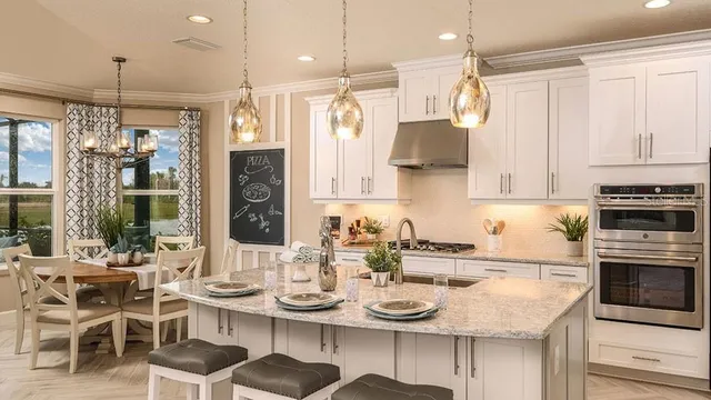 a kitchen with stainless steel appliances kitchen island granite countertop a table chairs and a refrigerator