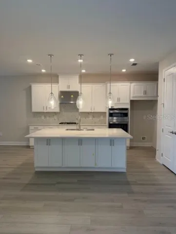 a kitchen with kitchen island granite countertop a white stove top oven and white cabinets