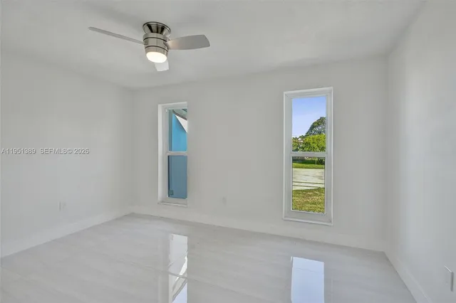 an empty room with windows and ceiling fan