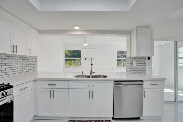 a kitchen with white cabinets and sink