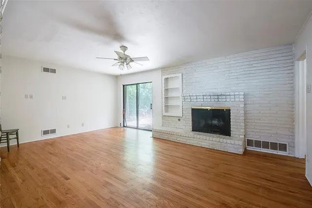 a view of empty room with wooden floor and fireplace