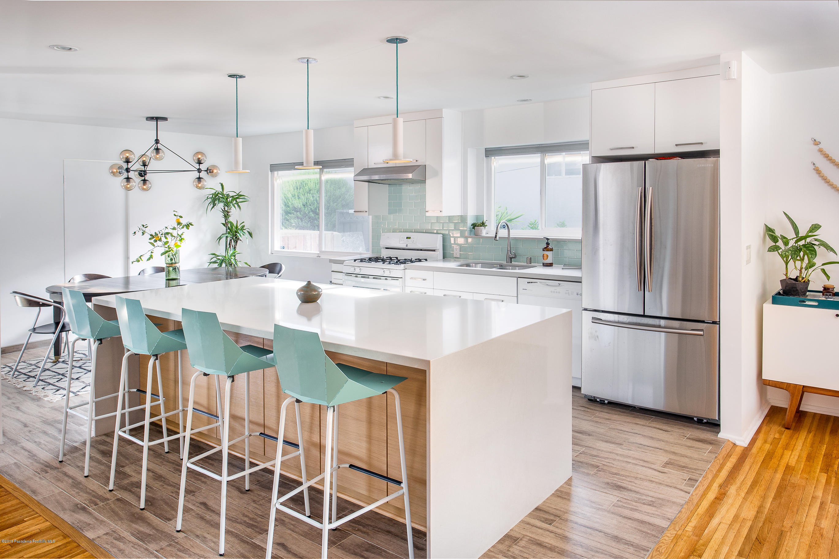 a kitchen with stainless steel appliances a dining table chairs a sink and dishwasher a refrigerator with wooden floor