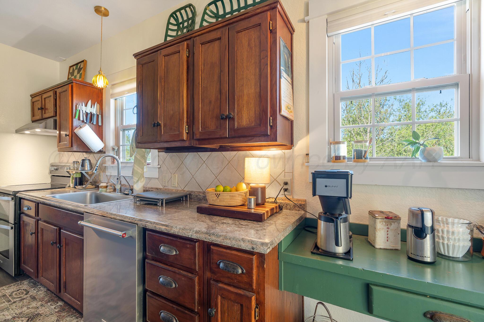 1401 3rd Avenue Canyon, TX 79015 - Photo 19 of 40 a kitchen with granite countertop wooden cabinets a sink and a window