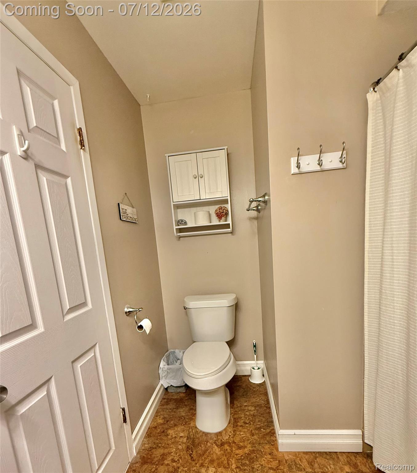 2033 Avonstoke Road Rochester, MI 48307 - Photo 14 of 26 Bathroom featuring a white toilet, wood-finish flooring, a wall-mounted storage cabinet, and a white shower curtain