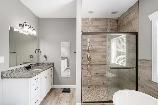 a bathroom with a granite countertop sink a toilet a mirror and shower