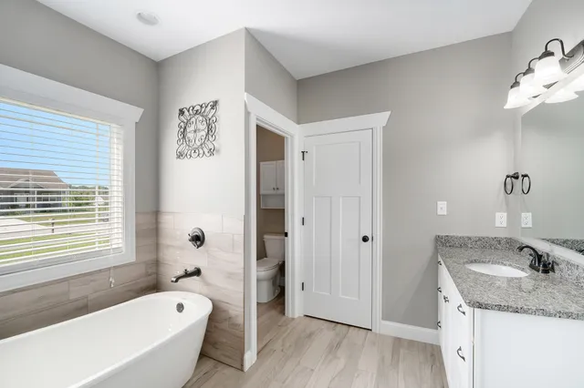 a bathroom with a granite countertop tub a sink and a large mirror
