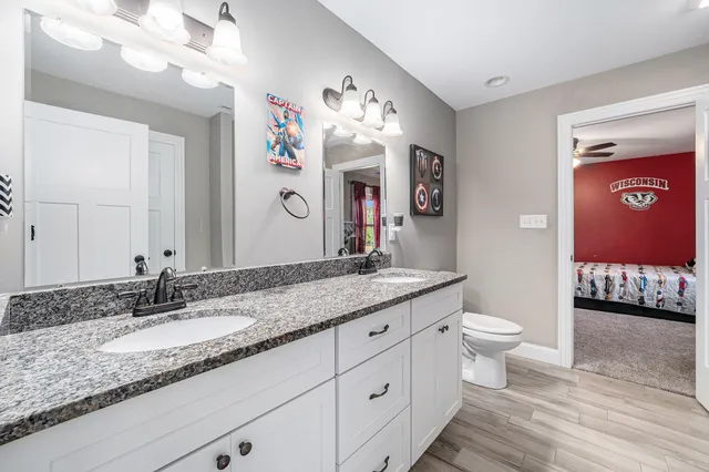 a bathroom with a granite countertop sink mirror vanity and toilet