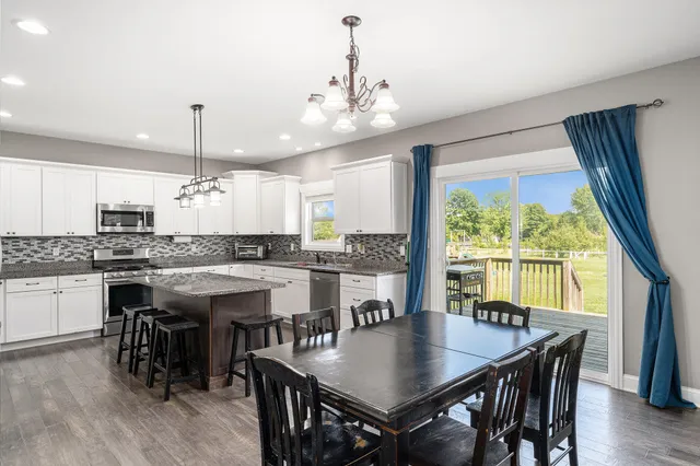 a kitchen with stainless steel appliances granite countertop a kitchen island hardwood floor sink stove dining table and chairs