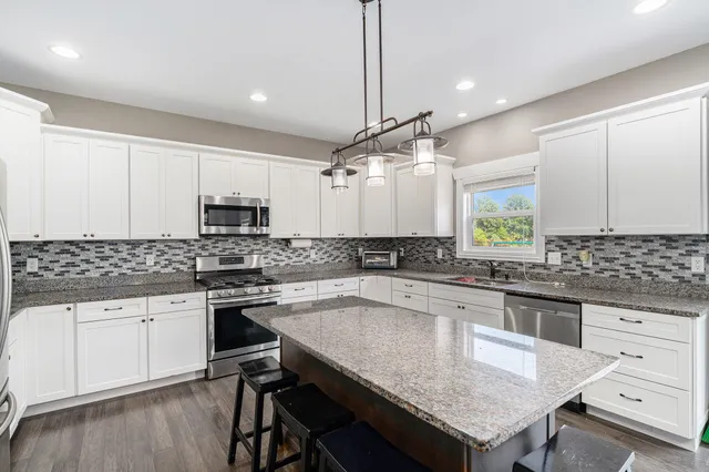 a kitchen with granite countertop a sink stove cabinets and wooden floor