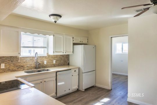 1521 South McCall Street Ridgecrest, CA 93555 - Photo 11 of 39 a kitchen with a refrigerator a sink and cabinets