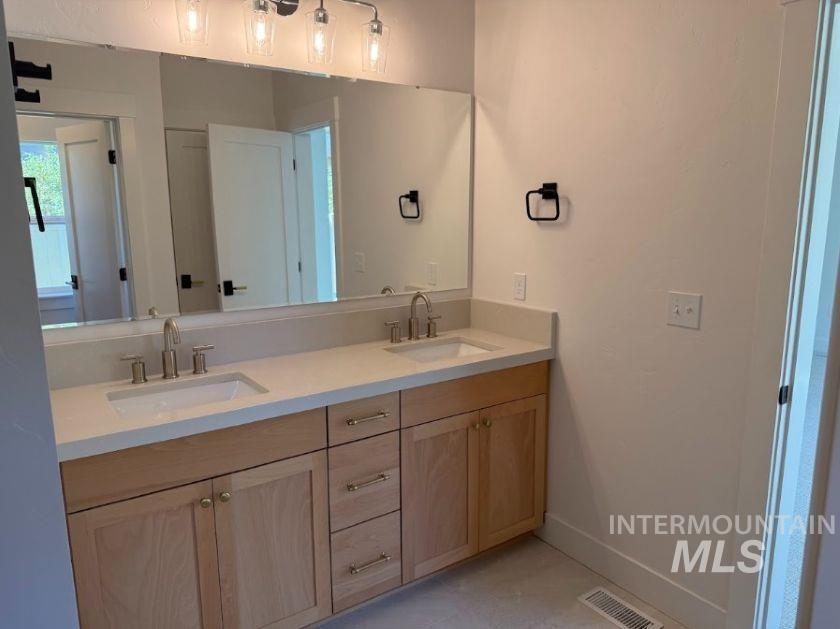 755 West Wrangler Street Meridian, ID 83646 - Photo 8 of 35 Dual vanity with light wood-finish cabinetry, brushed nickel hardware, and an integrated countertop with two sinks
