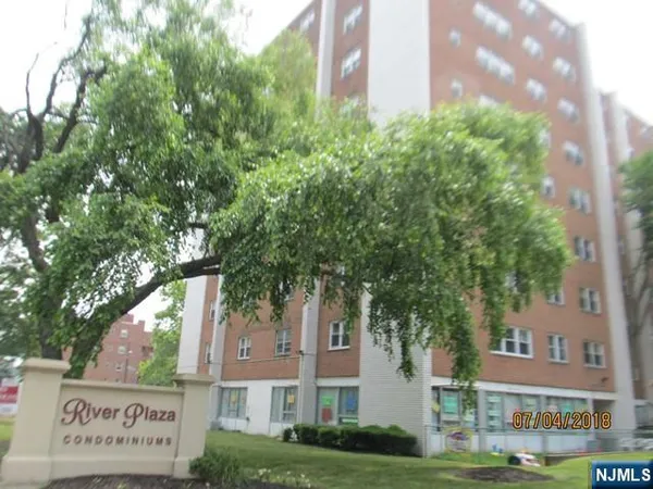 a front view of a multi story residential apartment building with yard and green space
