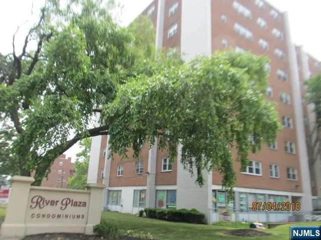 a front view of a multi story residential apartment building with yard and green space