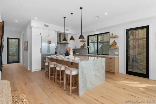 a kitchen with stainless steel appliances kitchen island granite countertop a table chairs and a refrigerator