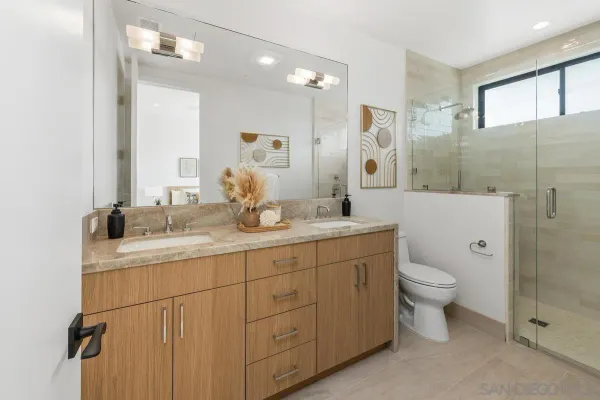 a bathroom with a double vanity sink toilet and shower
