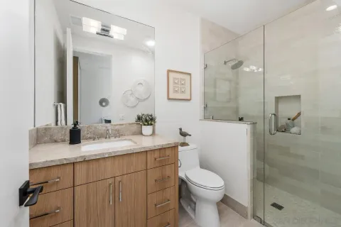 a bathroom with a granite countertop sink toilet a mirror a vanity and shower