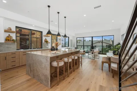 a large kitchen with kitchen island a large window a sink and stainless steel appliances