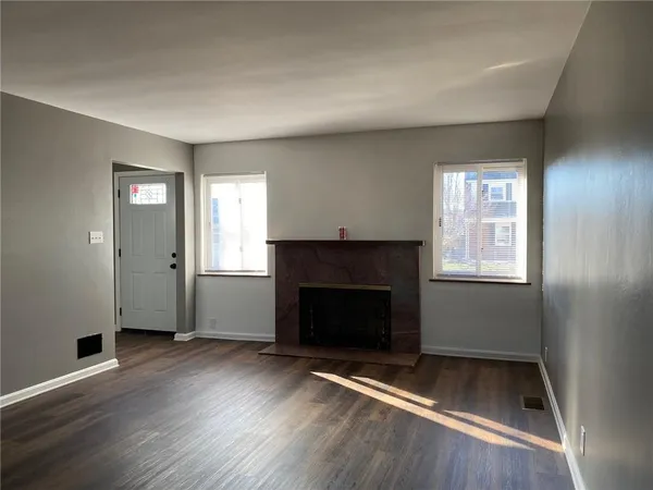 an empty room with wooden floor a fireplace and windows