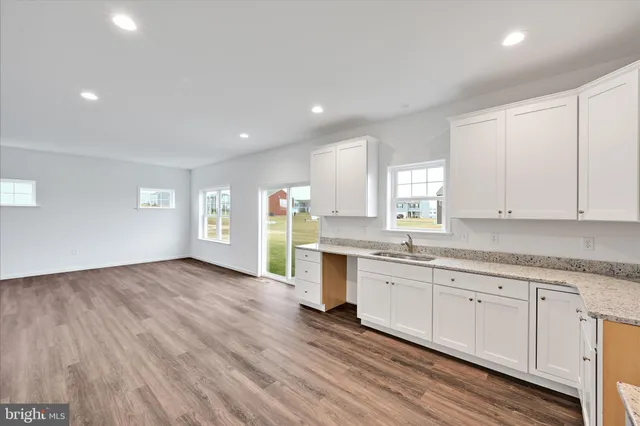 a kitchen with granite countertop white cabinets and wooden floor