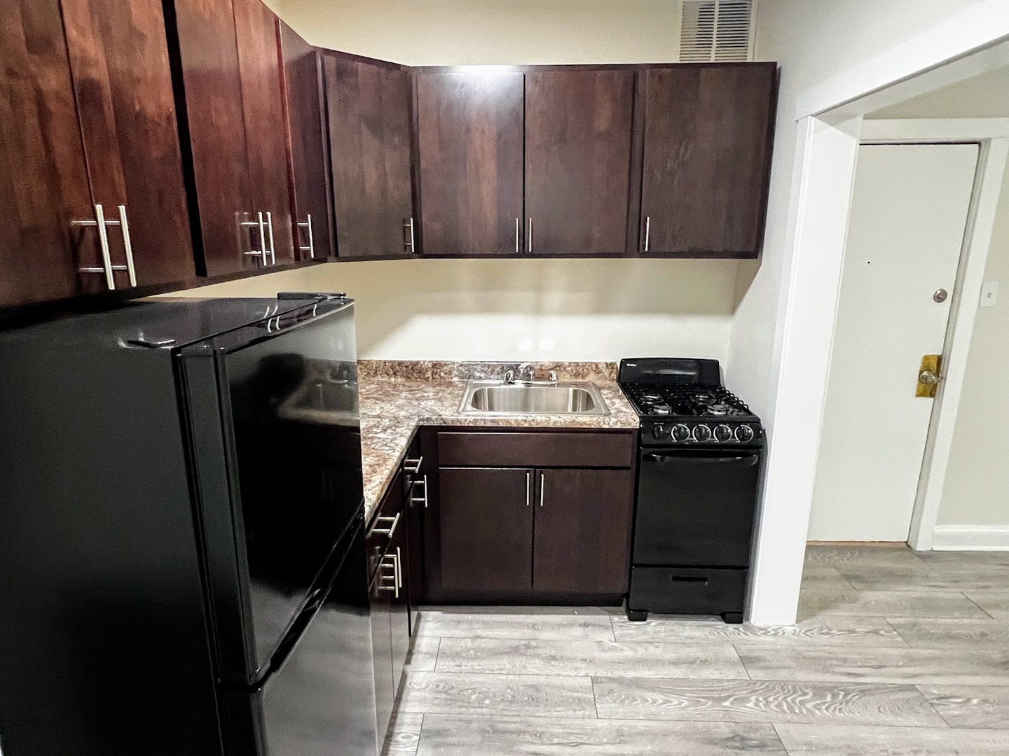 839 West Sheridan Road, Unit 422 Chicago, IL 60613 - Photo 6 of 10 a kitchen with granite countertop a stove and a refrigerator with wooden cabinets