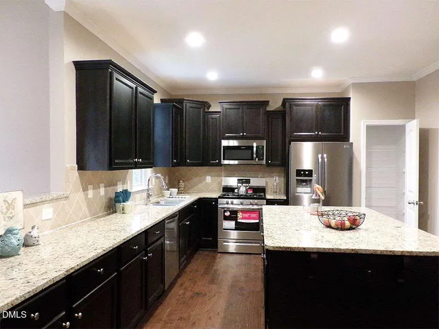 a kitchen with kitchen island granite countertop a sink stainless steel appliances and cabinets