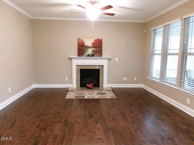 a view of an empty room with wooden floor fireplace and a window