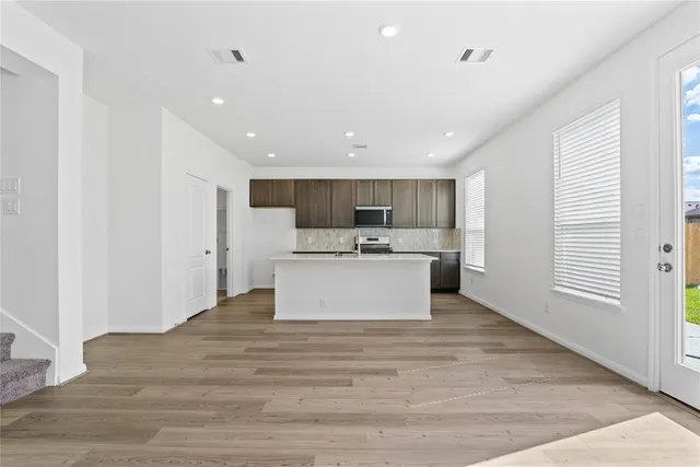 a view of a kitchen with kitchen island a sink a stove and wooden floors