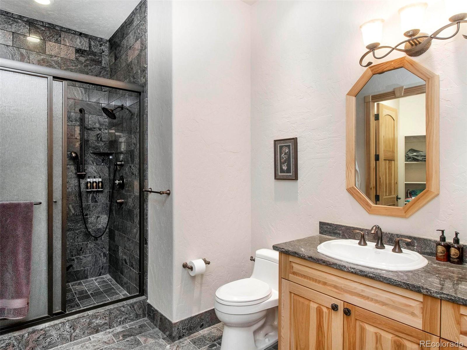 577 Bear Meadow Trail Evergreen, CO 80439 - Photo 23 of 40 a bathroom with a granite countertop sink toilet and shower