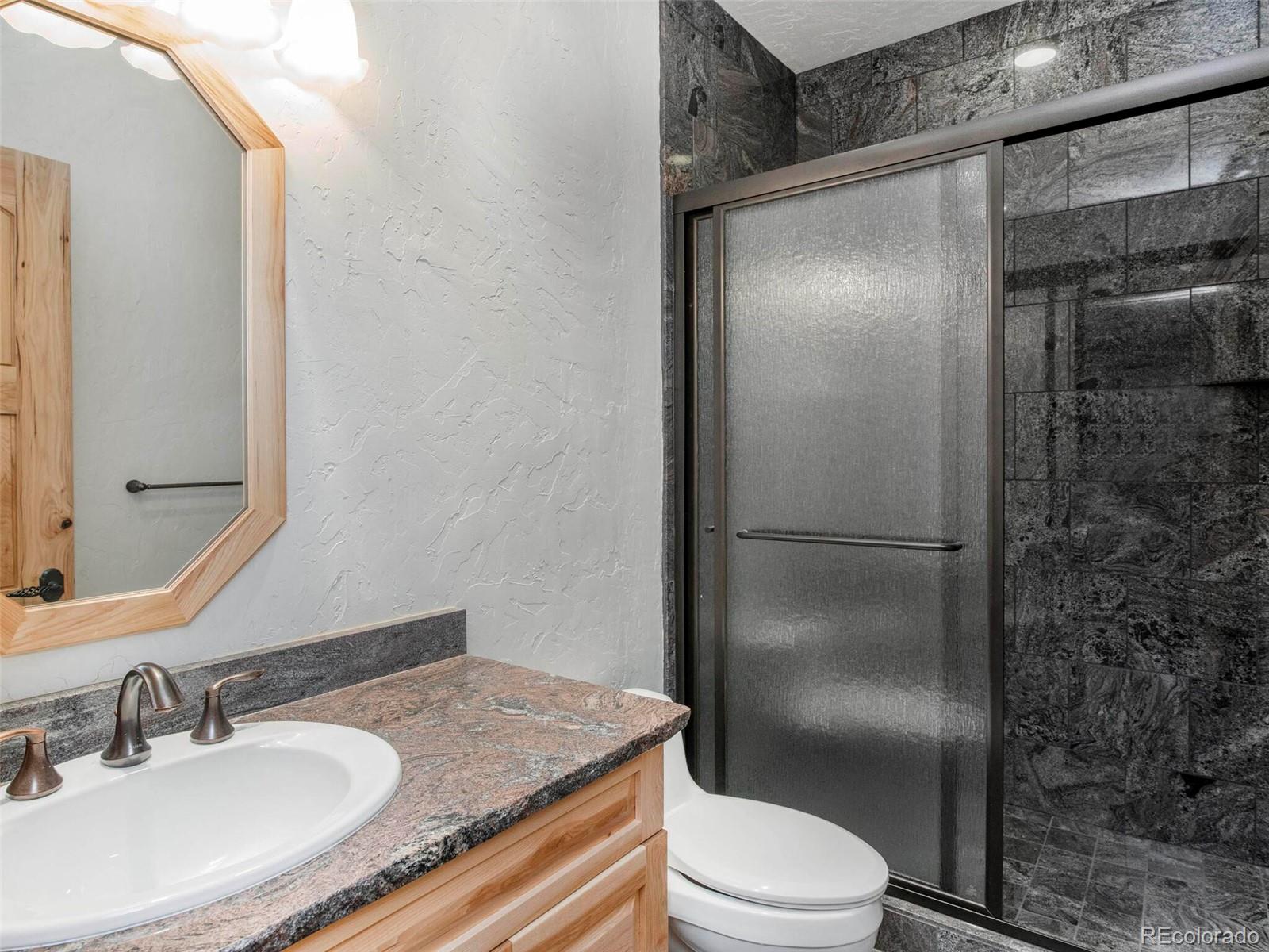 577 Bear Meadow Trail Evergreen, CO 80439 - Photo 35 of 40 a bathroom with a granite countertop sink toilet and shower