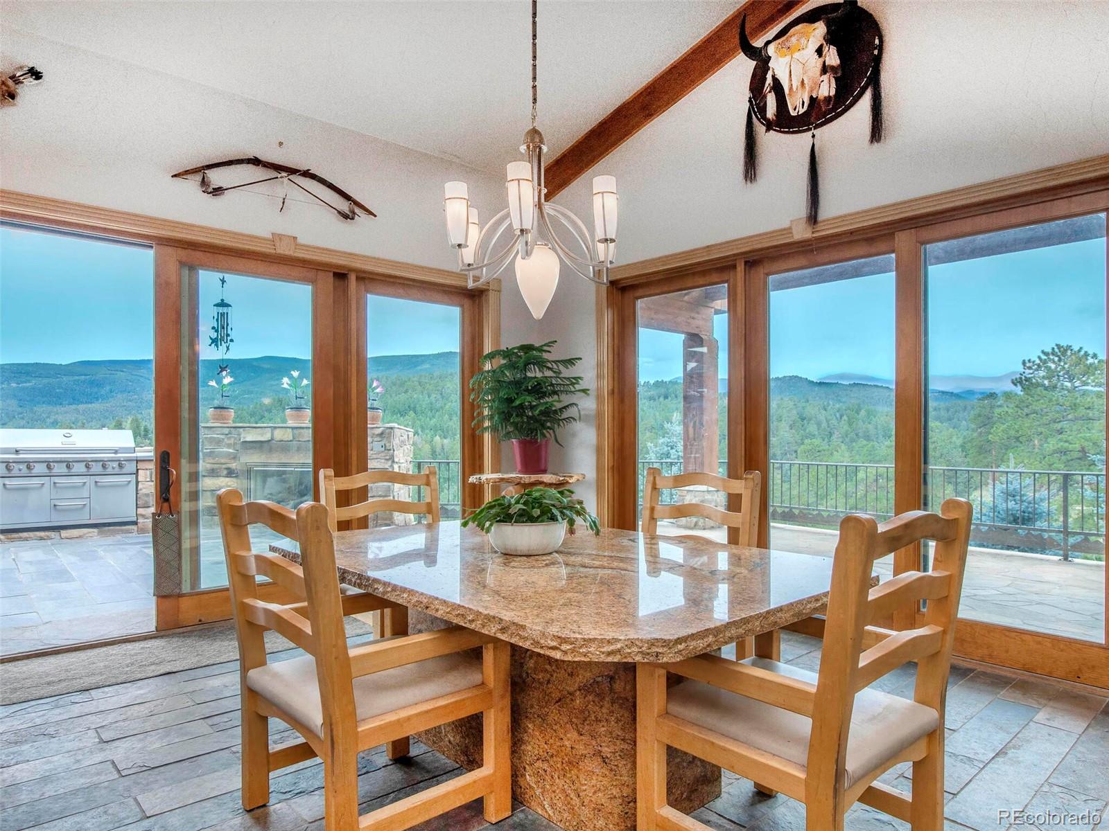 577 Bear Meadow Trail Evergreen, CO 80439 - Photo 10 of 40 a view of a dining room with furniture large windows wooden floor and chandelier