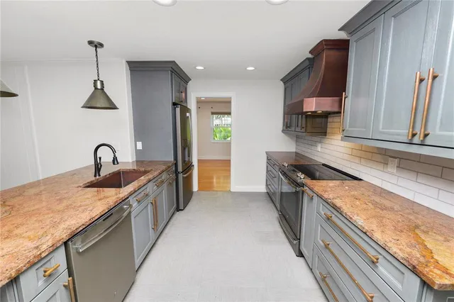 a large kitchen with stainless steel appliances granite countertop a sink and a stove top oven