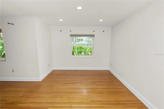 a view of empty room with wooden floor and window