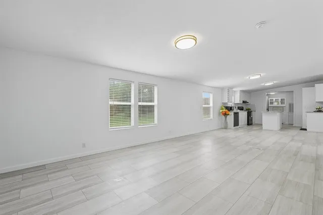a view of empty room with wooden floor and a window