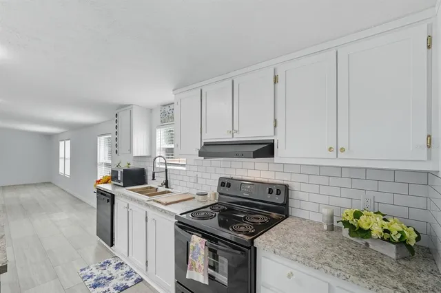 a kitchen with stainless steel appliances granite countertop a stove a sink and a white cabinets