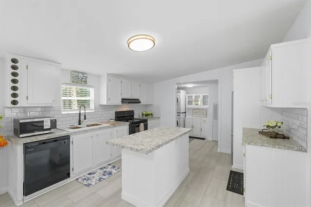 a kitchen with granite countertop a stove sink and refrigerator