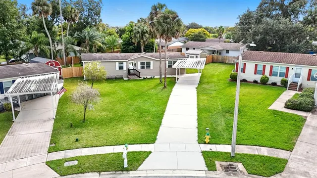 a view of a white house with a big yard plants and large trees