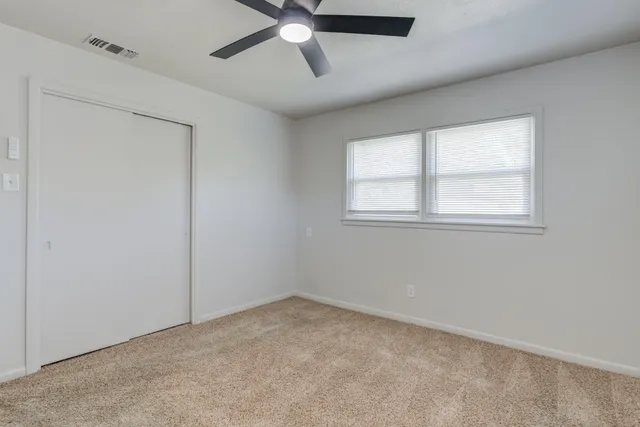 an empty room with a window and a fan